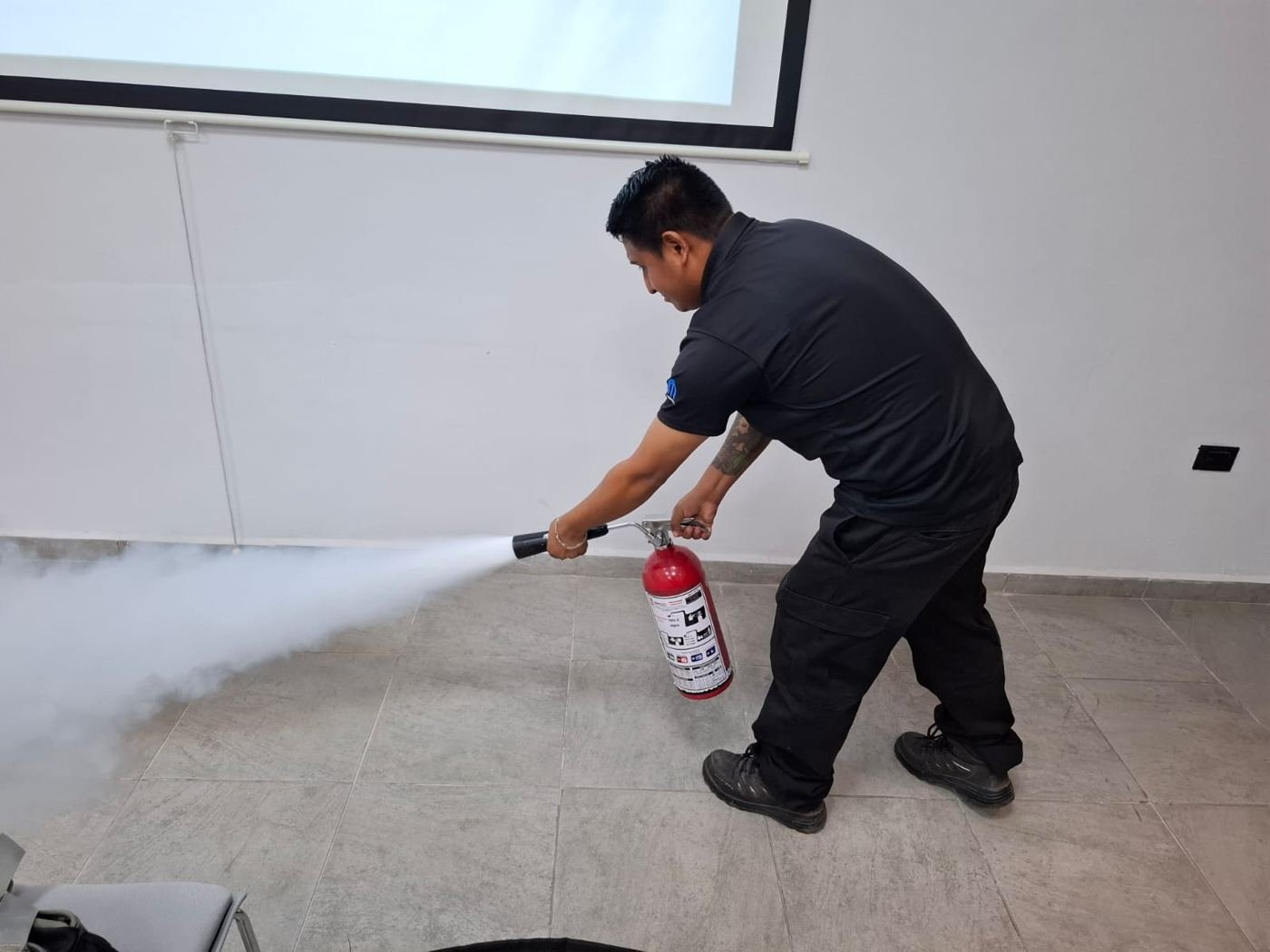 Participante descargando extintor en sala de capacitación