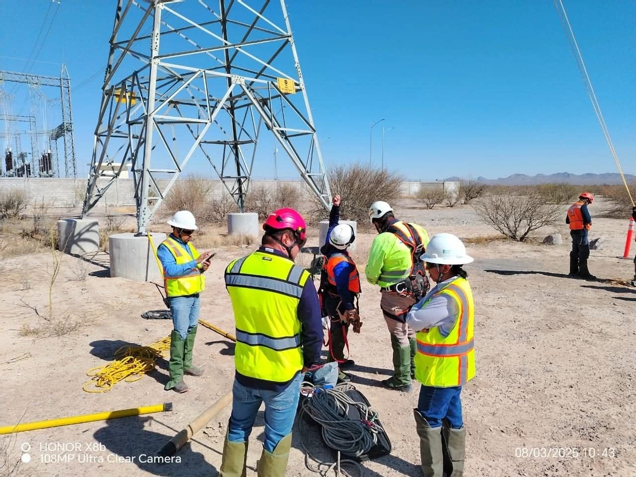 Equipo con chalecos reflejantes al pie de una torre de alta tensión